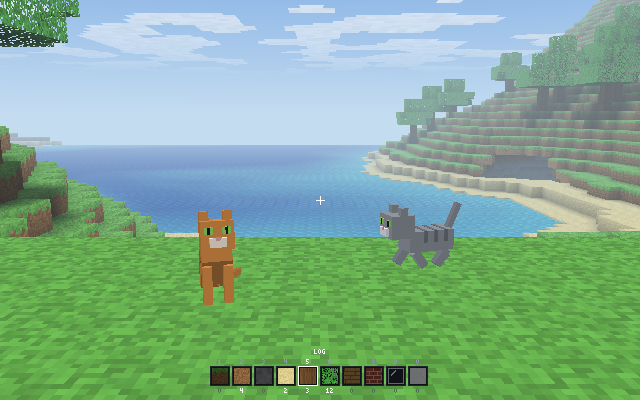 blocks: two cats on the grass above a blue bay, one sitting and one walking, with a wooded hill and clouds behind them